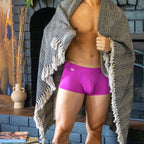 Person wearing bright pink boxer briefs with a patterned towel draped over their shoulders, standing in a casual setting.