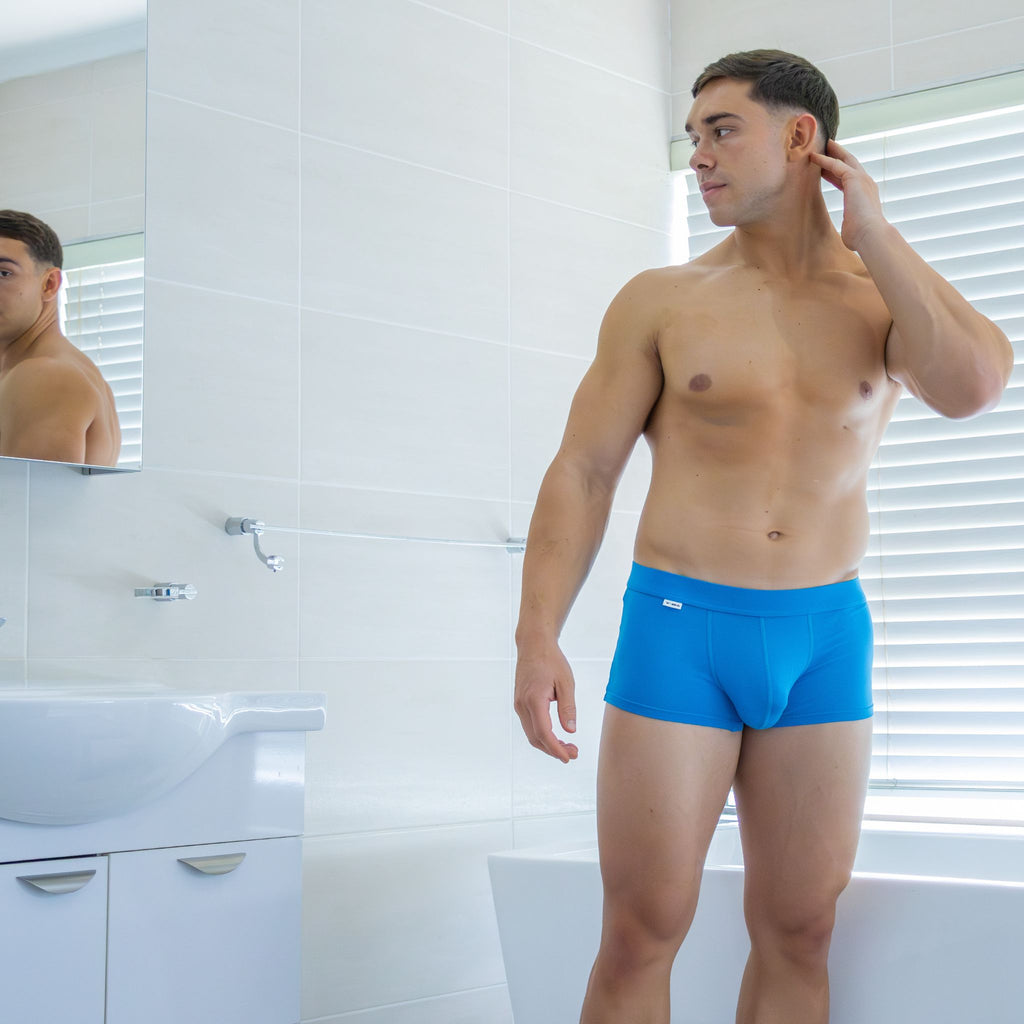 Man wearing blue underwear in a bathroom