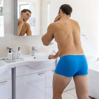 Man wearing blue underwear in a bathroom